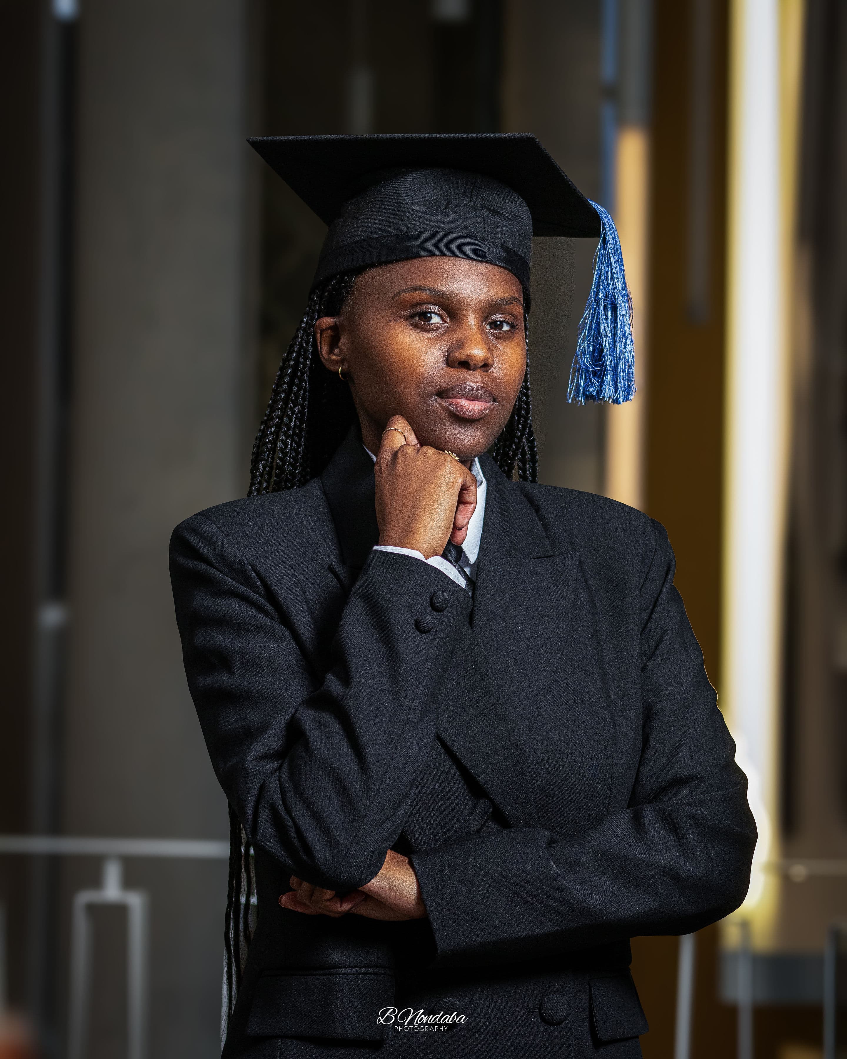 A Black woman in a graduation cap with a blue tassel and black blazer.